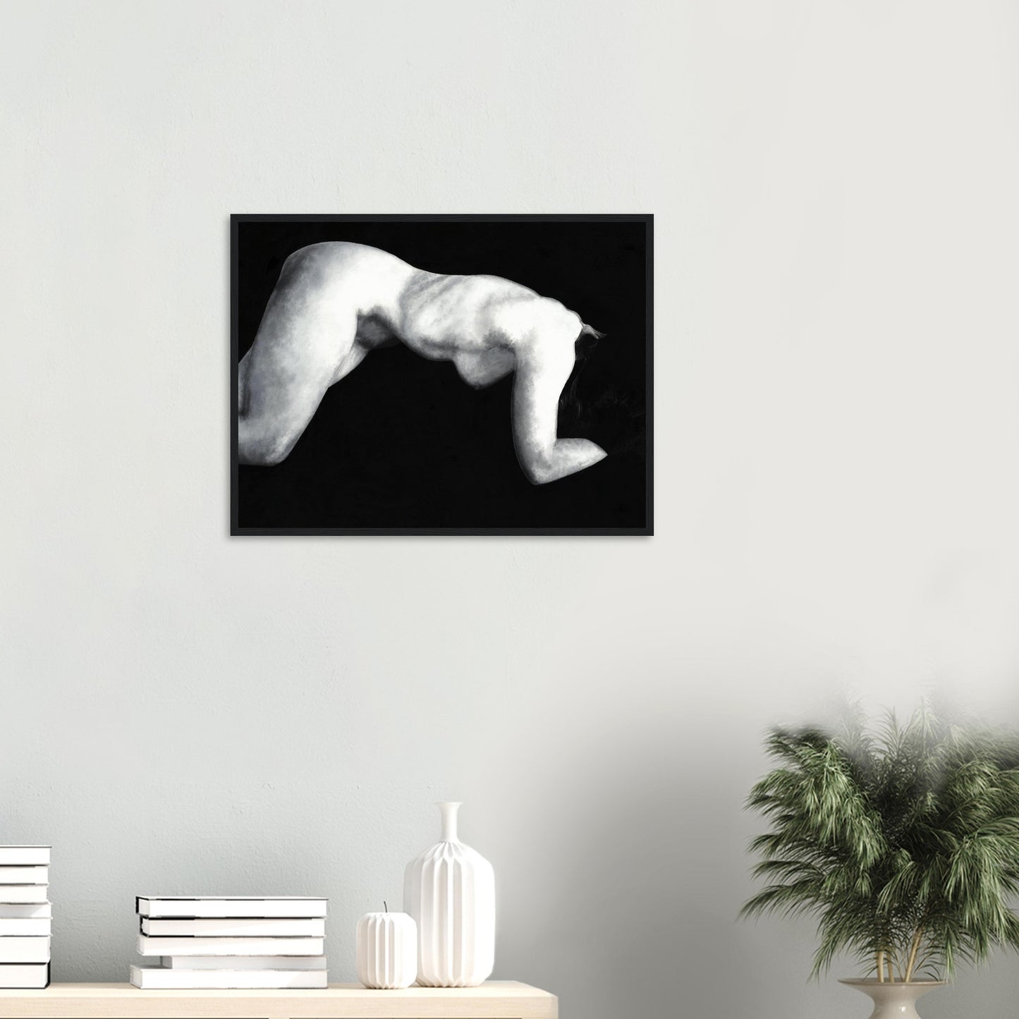 Framed black and white artwork of a reclining nude female figure on a wall above a shelf with decorative items.