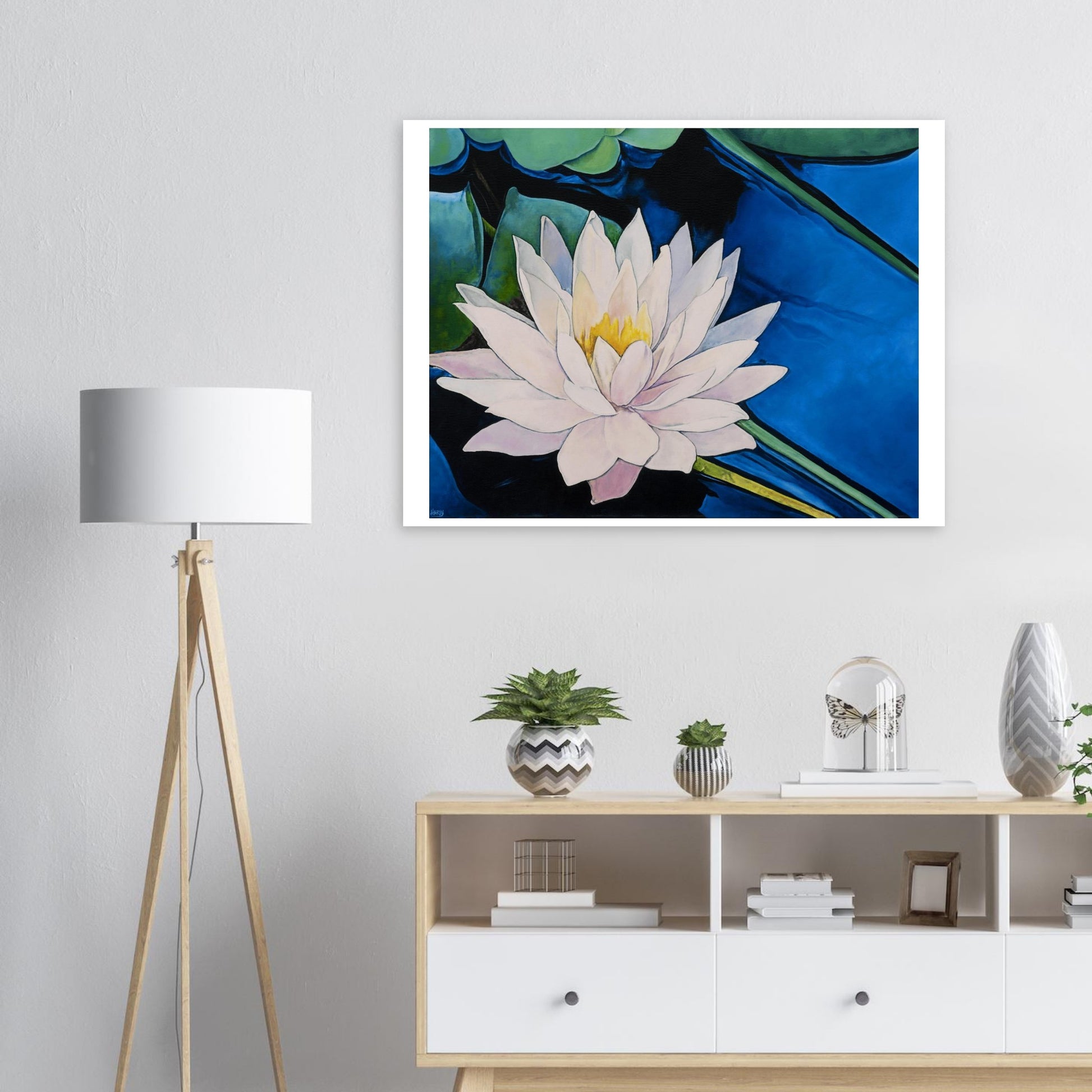 Framed artwork of a water lily on a wall above a wooden cabinet with decorative items.