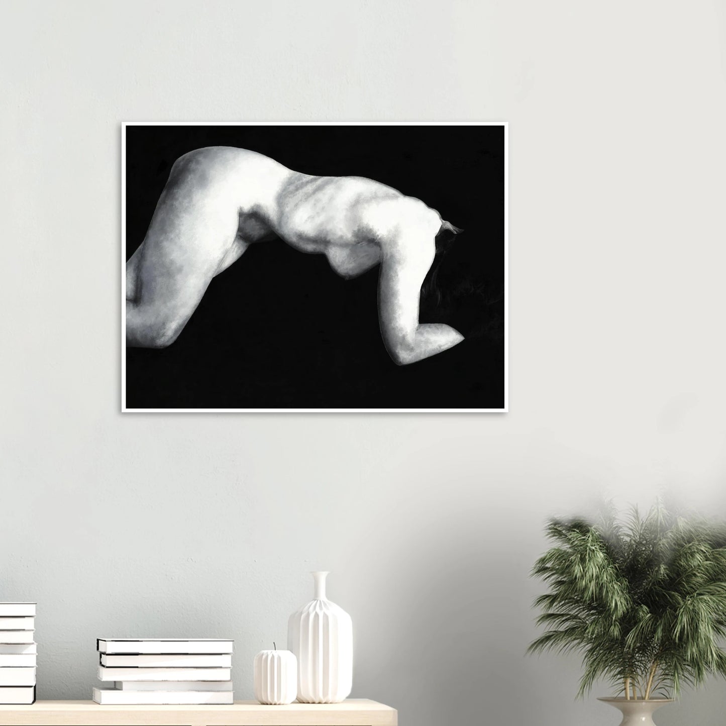 A black and white artwork print of a reclining nude figure on a wall above a shelf with decorative items.