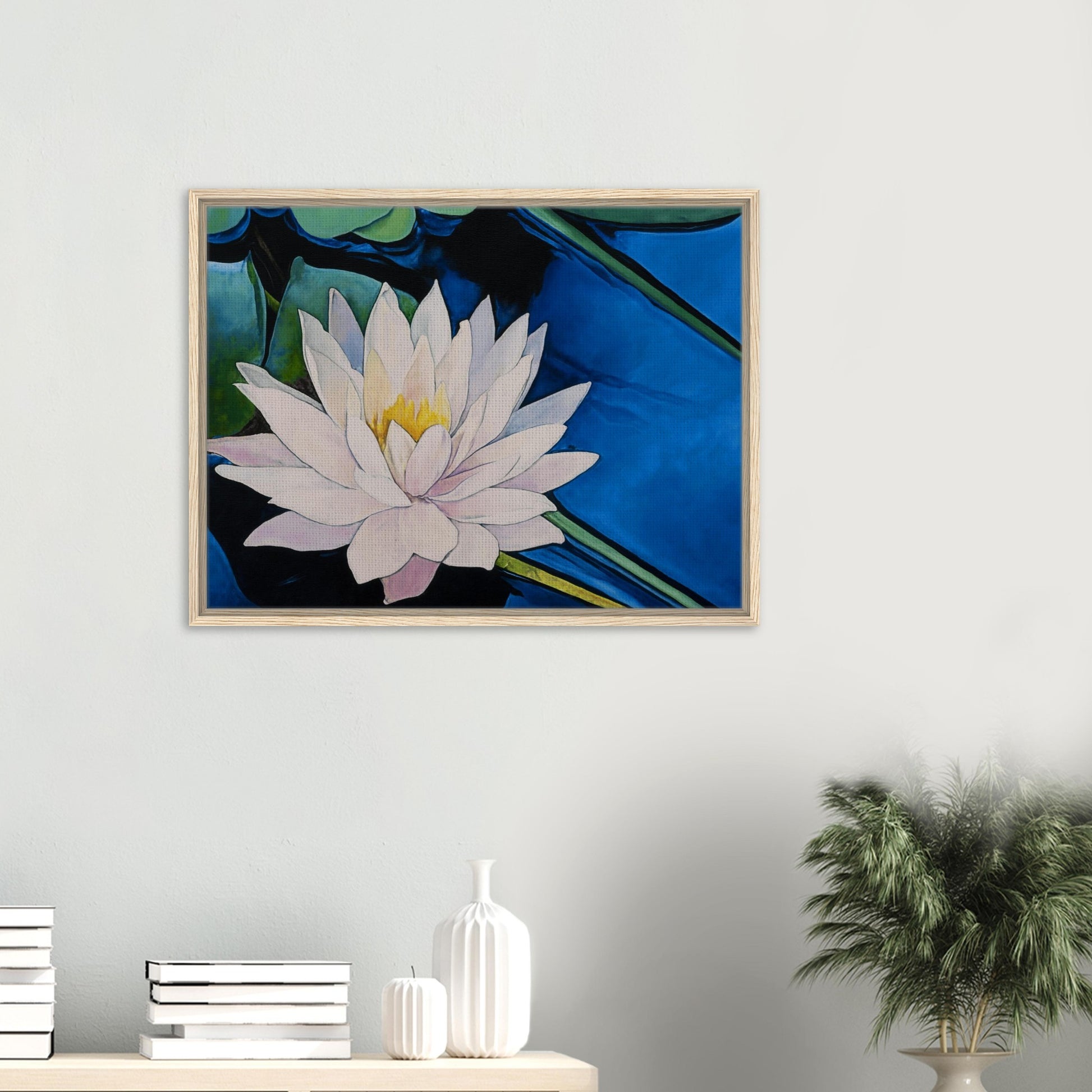 Framed artwork of a watercolor flower on a wall with decor items below.