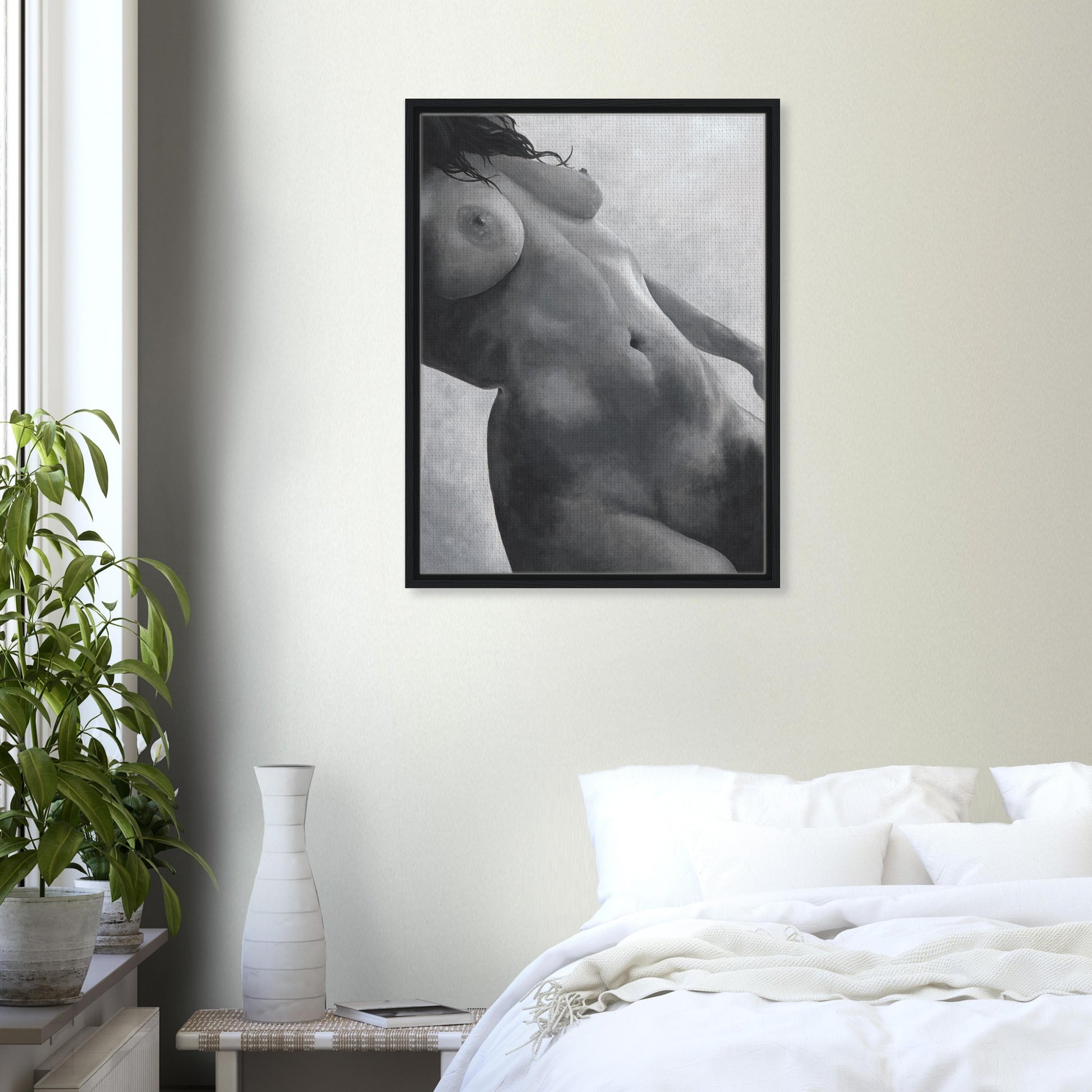 Framed black and white artwork of a nude figure on a wall above a bed in a bedroom.