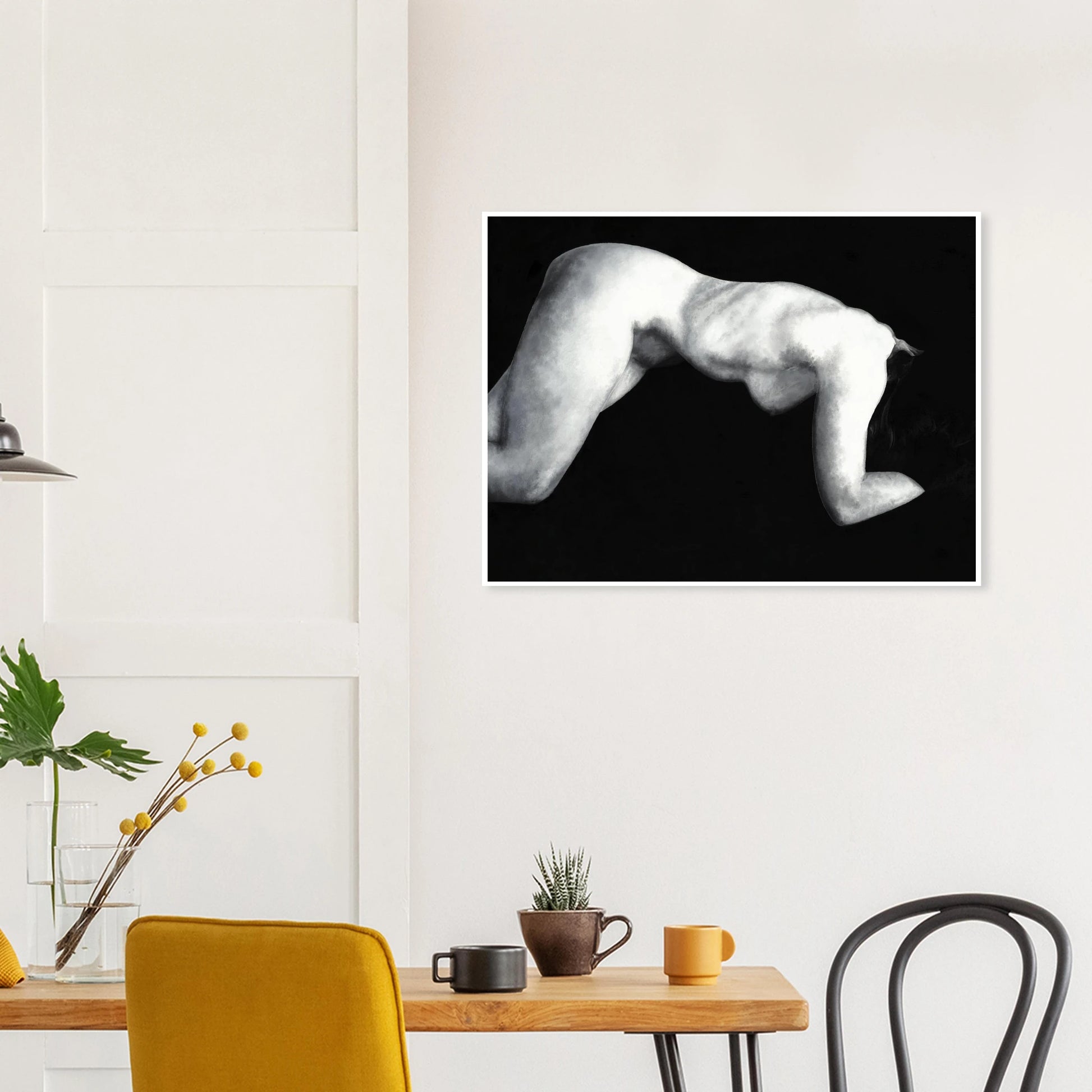A black and white artwork print of a reclining nude figure on a wall above a table with decor items